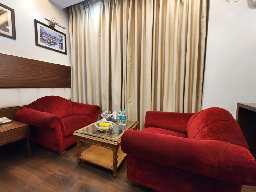 Cozy seating area with plush red sofas, center table, and elegant interiors in a Premium Room at Hotel Surya Shimla near Mall Road.